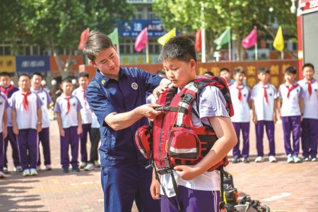 <br> ■5月12日,河北省遵化市第一实验小学的学生在消防救援人员的帮助下体验救生衣穿戴 ■供图/新华社<br><br>